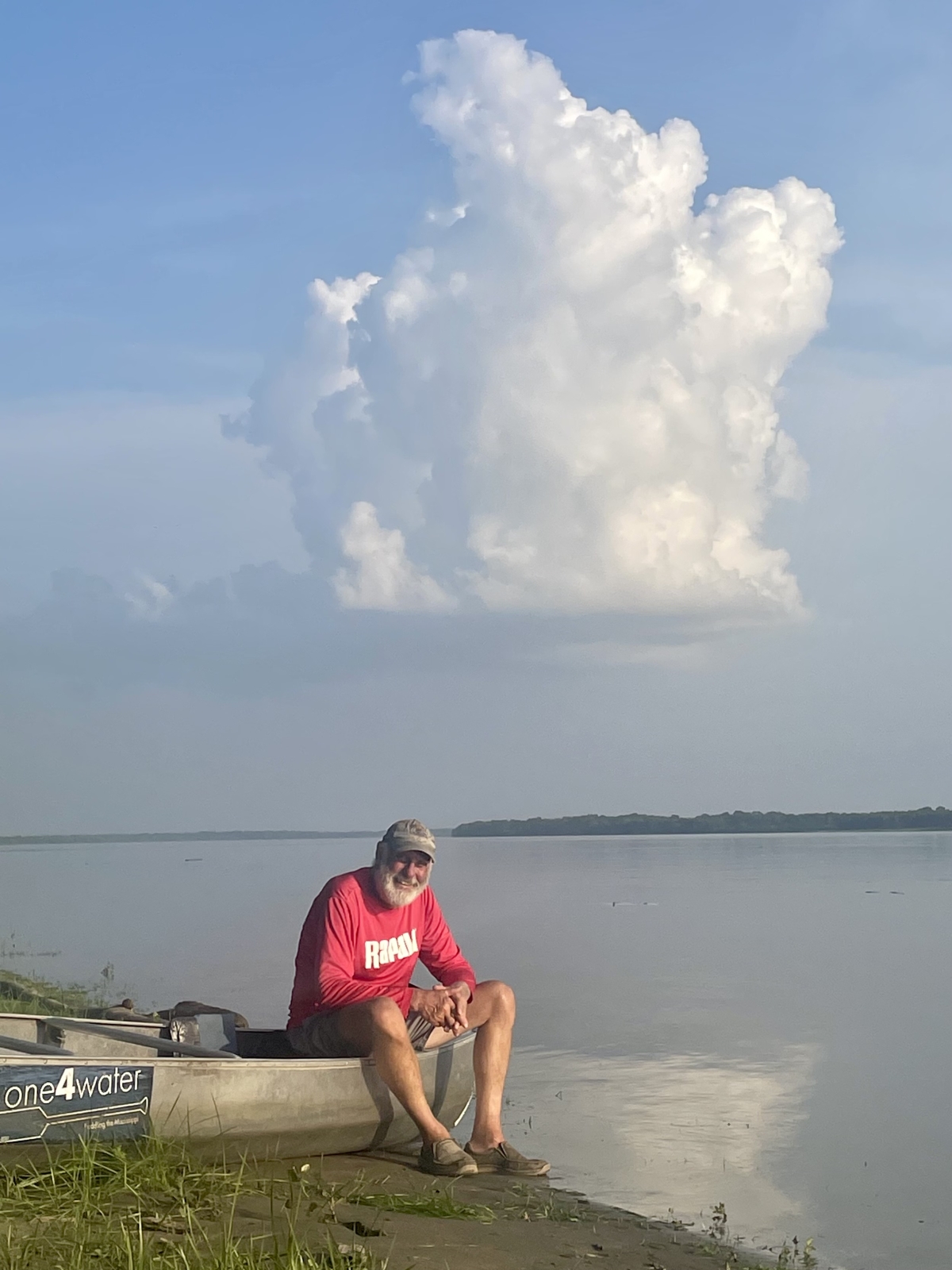 Man sitting on canoe at water's edge.